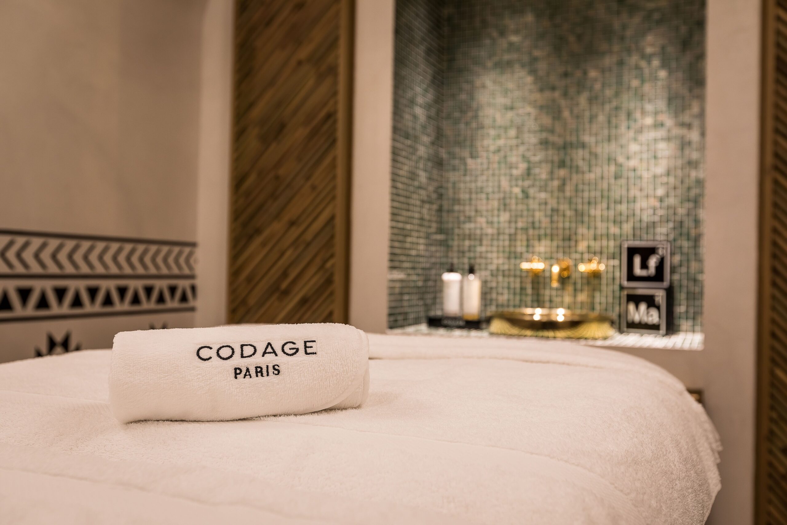 Spa room, with single bed in the middle with a towel on top of it. There is a sink on the far away wall