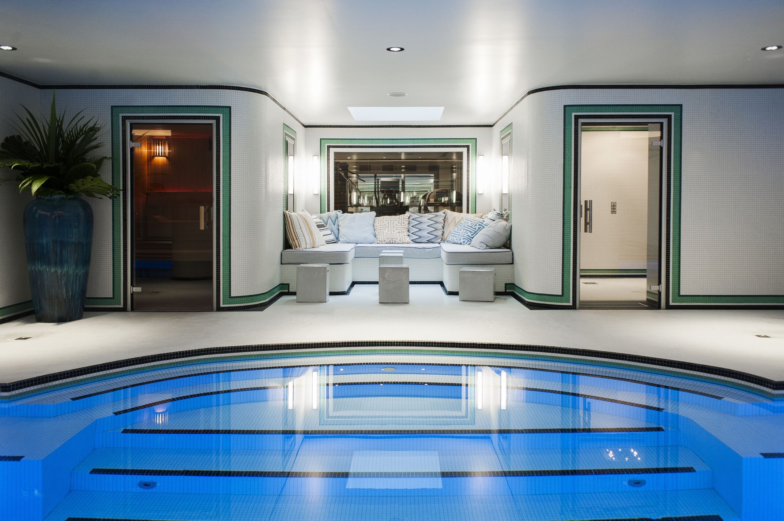 crescent shaped pool with sauna and hamman rooms in the surroundings as well as cushions to lay in
