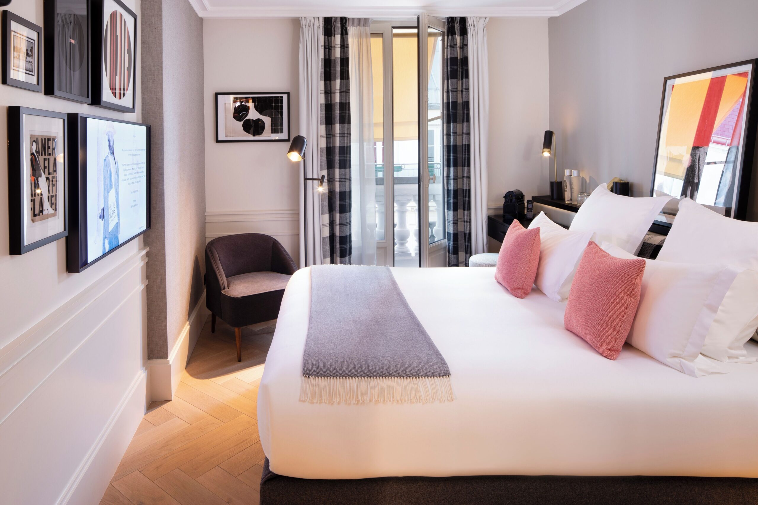 Hotel room with double bed, TV, balcony, and side chair