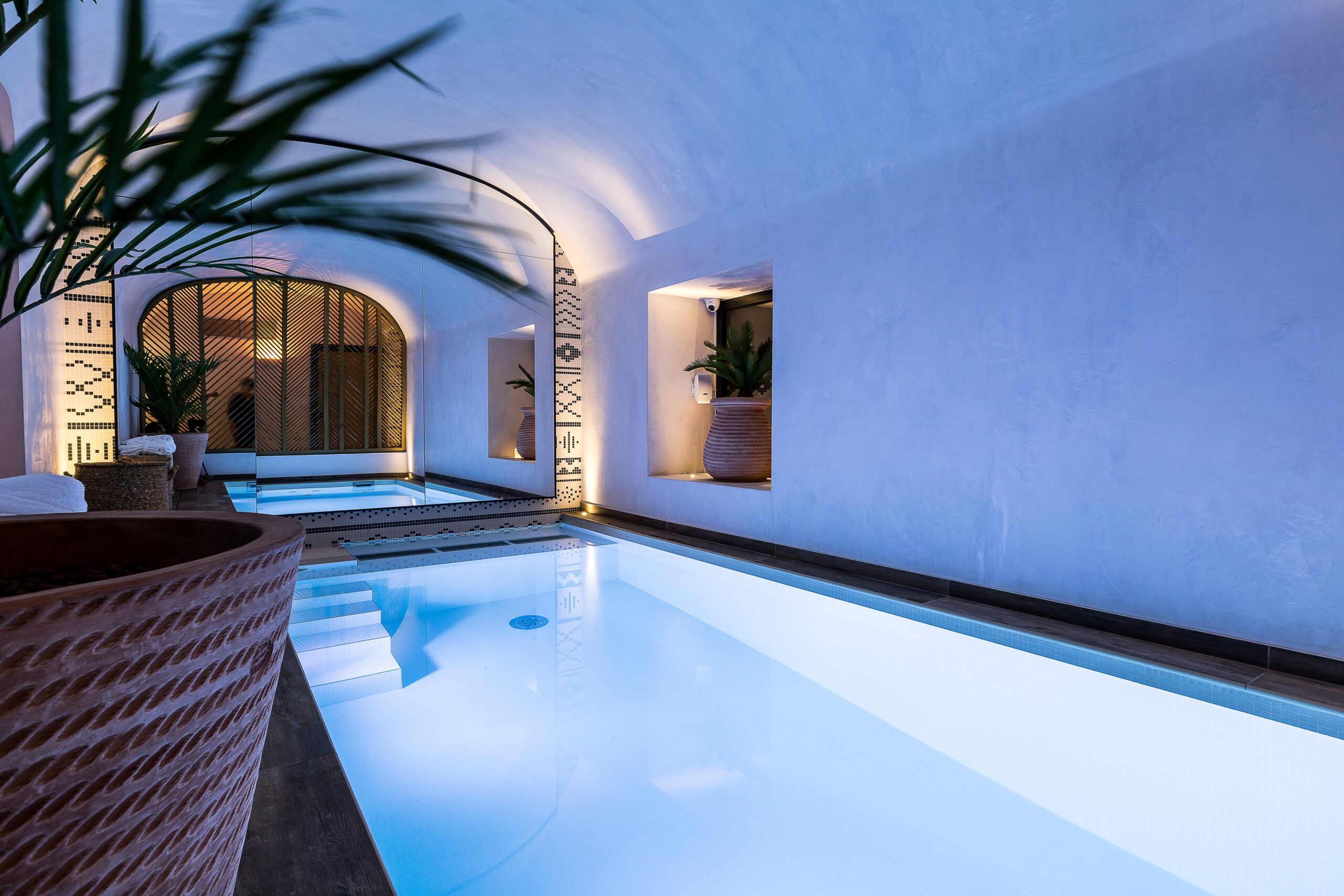 Long rectangular pool with small side steps entering the pool, and a wide arched mirror on one of the walls
