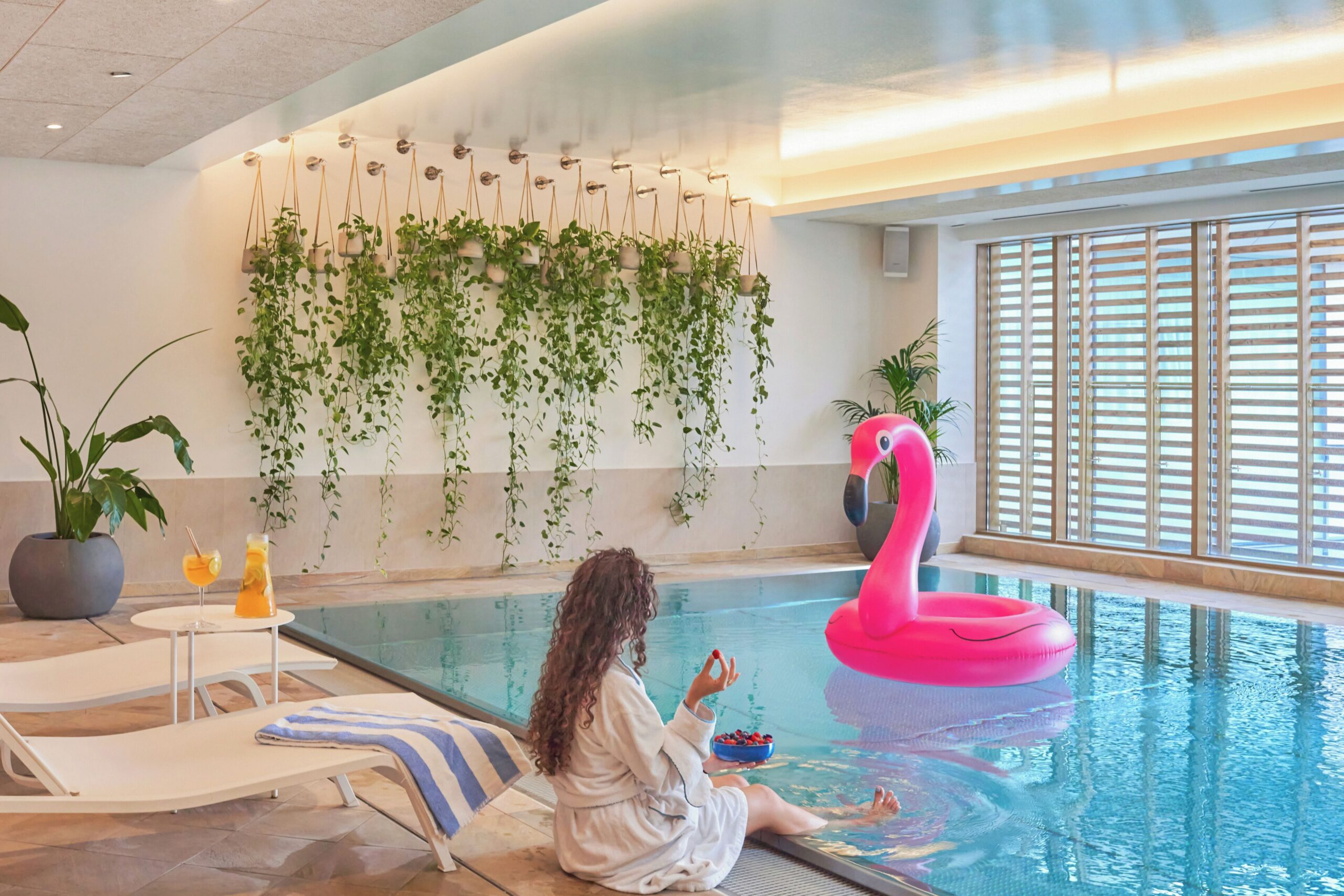 rectangled pool, with plants on one side of the wall and chairs to lay dow in