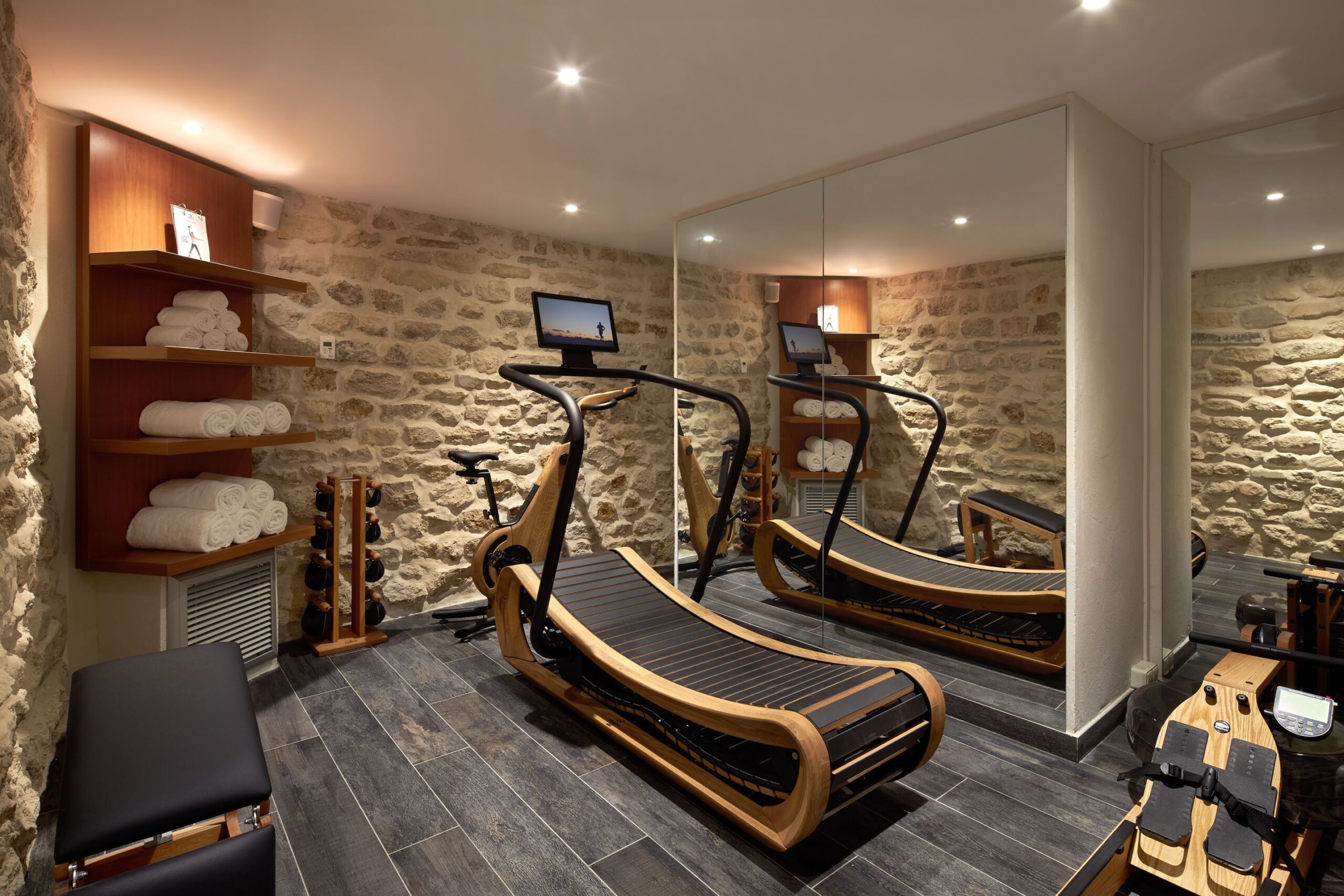 Fitness center with wide mirror, running machine, weights, and rowing machine