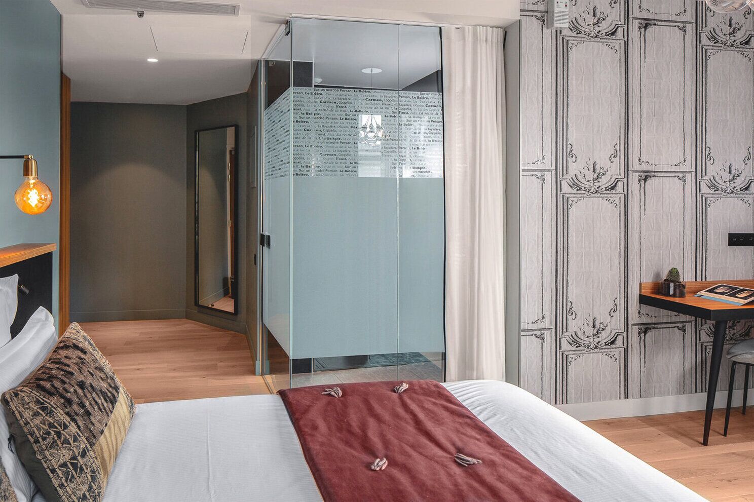 Room with a double bed close to a blind shower and a mirror on the far end